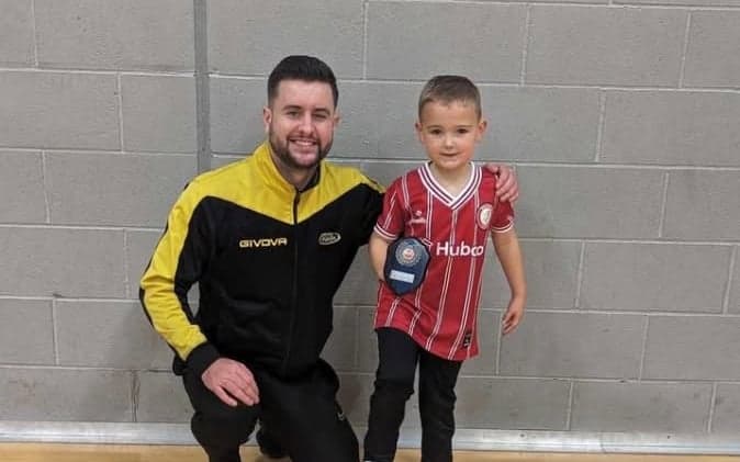 A young First Steps Soccer player with an award and their coach